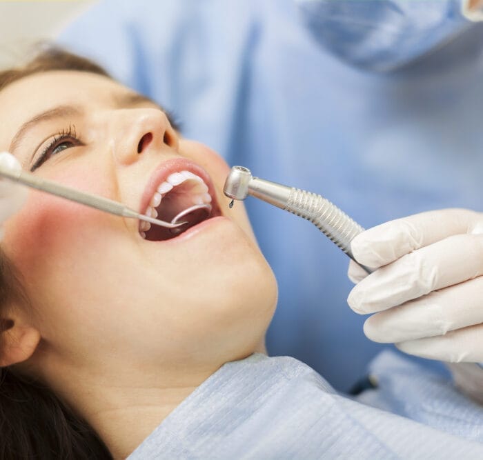 Professional dentist performing a thorough teeth cleaning procedure on a patient in a dental office.