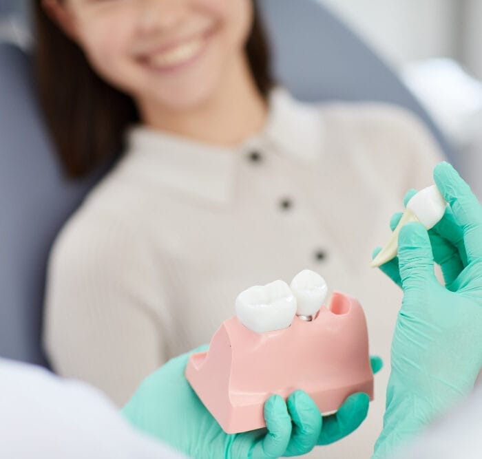 Doctor explaining dental health to a patient using a mouth-teeth model, highlighting proper brushing techniques and oral hygiene practices.