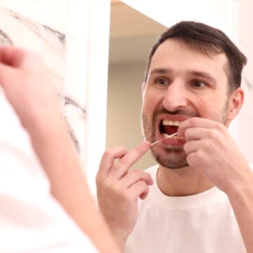 Health care, dental hygiene, people beauty concept. Smiling young man with floss cleaning teeth.