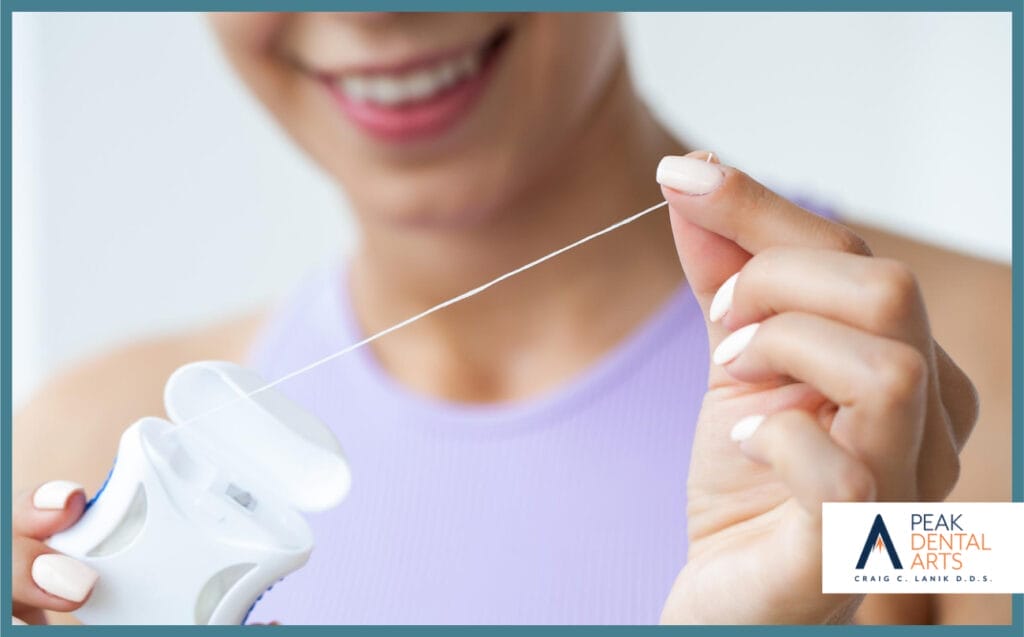 Woman pulling dental floss from a container, preparing to clean her teeth, with a focused expression.