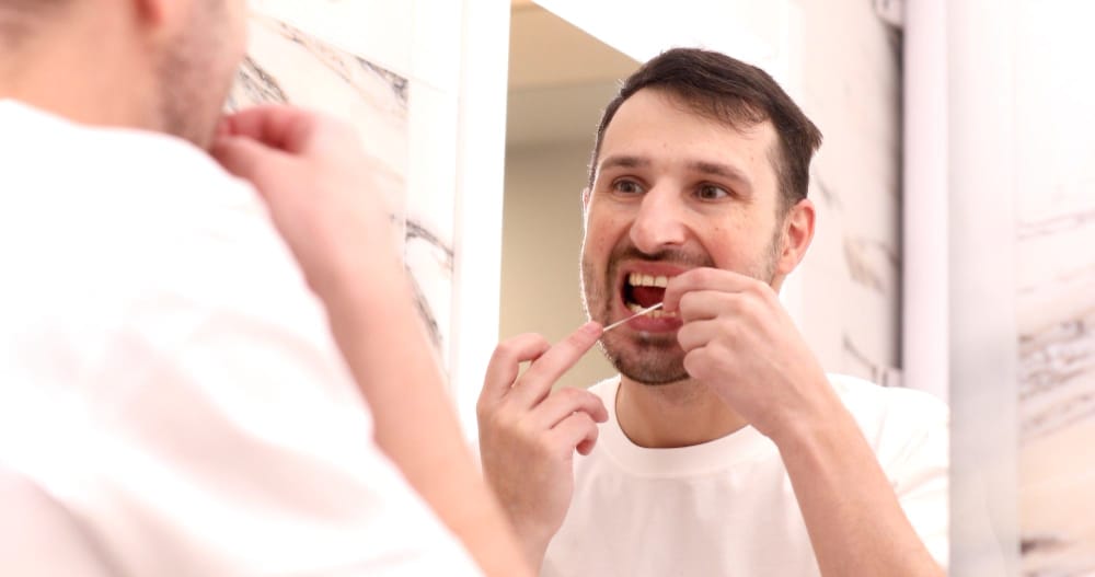 Health care, dental hygiene, people beauty concept. Smiling young man with floss cleaning teeth.