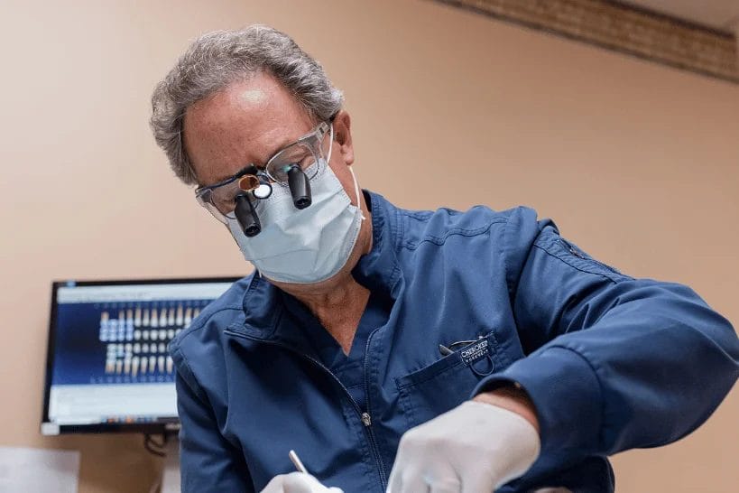 Male dentist wearing loupes performing dental treatment on patient